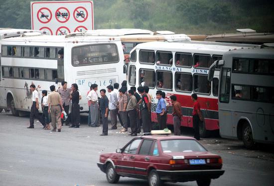 为了躲避超载检查，许多大巴司机在高速公路入口处等客。2004年6月13日，等客大巴聚集在合肥龙塘高速入口处，车内塞满了人。