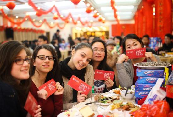 在华番邦留门生们手拿红包在校园食堂春节。新华网
