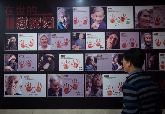 资料图片:2016年12月10日,一名与会者在观看纪实画册《90位幸存慰安妇实录》首发现场展示的书中照片。新华社记者 罗晓光 摄