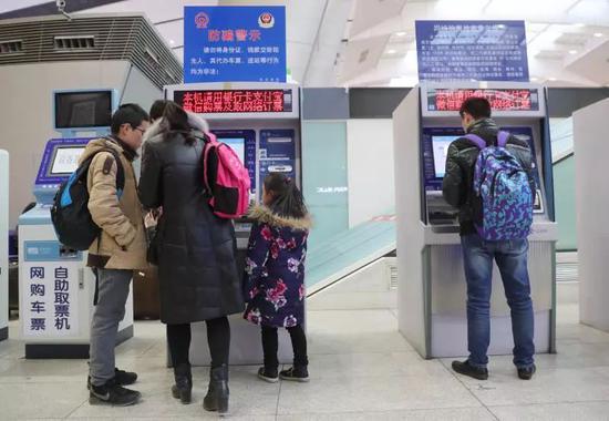 2018年2月7日，北京南站，自助取（售）票机前，人们正在取票。新京报记者尹亚飞 摄