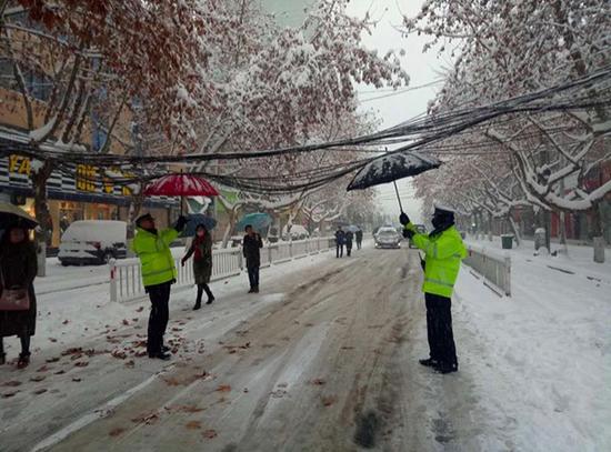 澎湃新闻:湖北谷城暴雪压塌电缆 辅警撑伞顶缆40分钟保通行