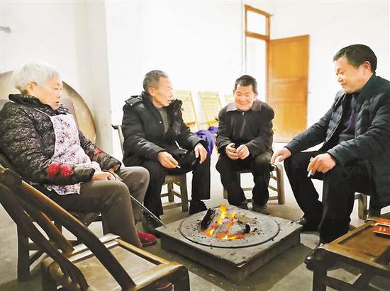 胡定宣（左三）和向正先（右一）、向家父母一起烤火聊天。记者 龙丹梅 摄