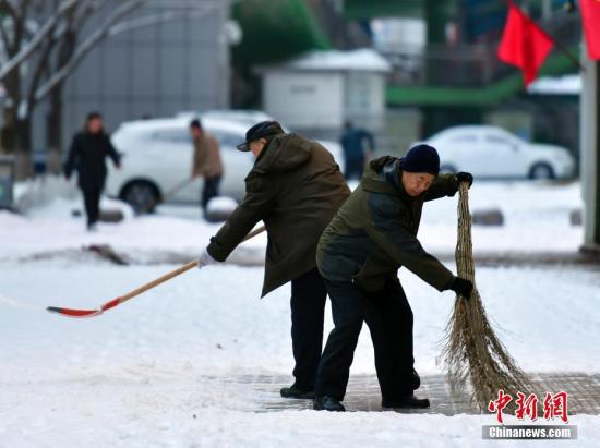 农历狗年正月初一，民众在乌鲁木齐街头清理人行道上的积雪。中新社记者 刘新 摄