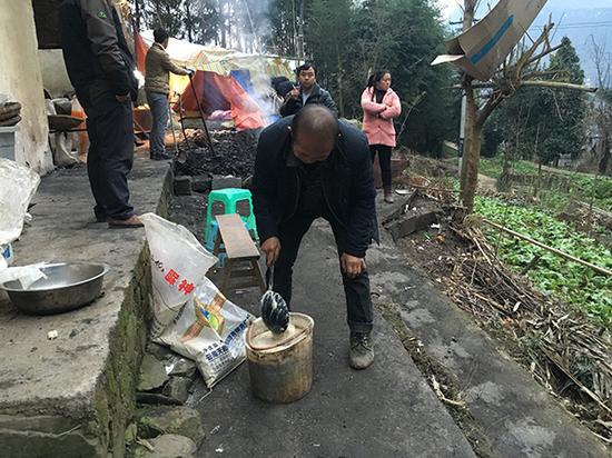 李明华的妹夫杨传玉（中）帮助李高愧喂牛喂猪。澎湃新闻记者 王鑫 摄