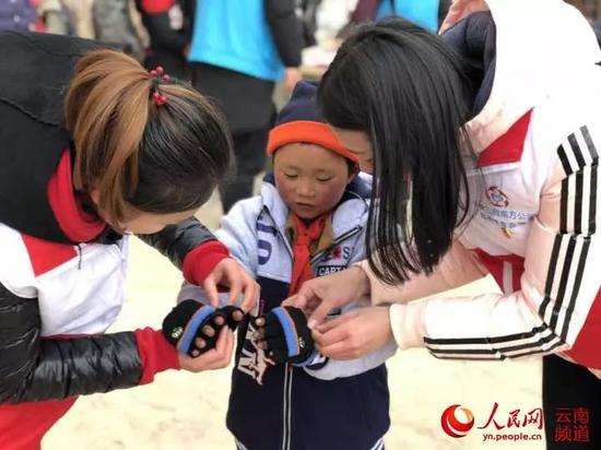 1月10日,中建三局志愿者在转山包小学为小满穿上棉衣、戴上手套。摄影:叶龙飞