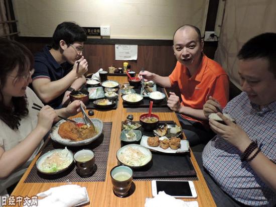 广州市的杨先生和同事一起吃日料。（《日本经济新闻》网站）