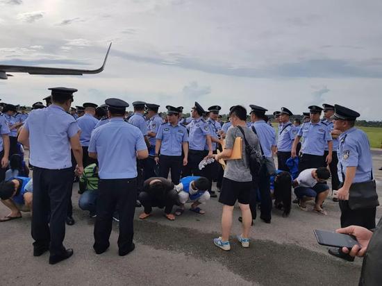 2017年8月，在柬埔寨暹粒国际机场，跨国电信诈骗嫌疑人在中国警方的押解下准备登机。新华社发