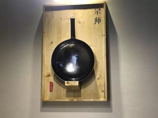 济南宽厚里某铁锅体验店里，王玉海打制的锅被叫做“宗师”系列锅，挂在墙上第一次序位置展示。