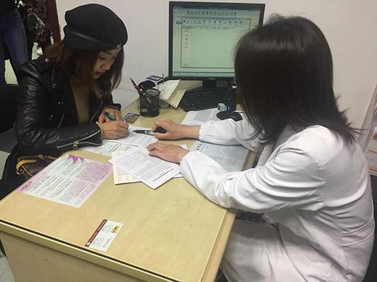 上海首位接种HPV四价疫苗的女性邱琼在接种前进行一次评估,签署接种知情同意书。 本文图片 澎湃新闻记者 陈斯斯