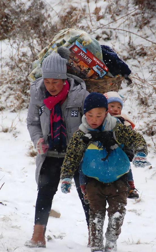 吉觉吉竹背着弟弟，和妈妈在山路上跋涉，前往申果乡沙苦新村的外公家。