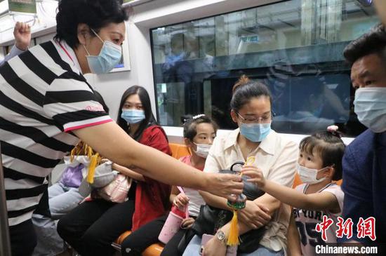 图为呼和浩特市文化旅游广电局副局长娜敏将代表草原形象的文创产品送给乘客。 王少晶 摄