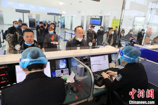 图为边检人员为乘客办理乘机手续。 塔娜 摄