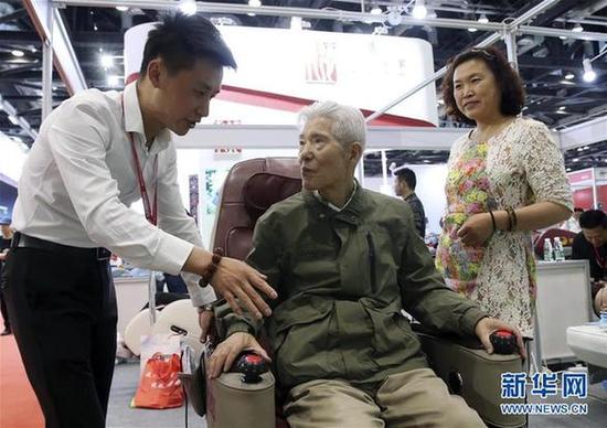 5月9日,一名老年人在博览会现场体验一款理疗设备。