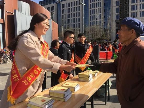 ↑工作人员为群众发放安全知识手册