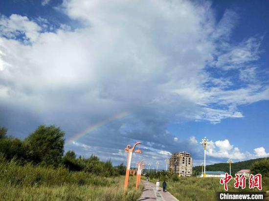 图为7月22日根河市区上空出现彩虹,晨练的群众穿上了厚厚的外套。 纪成成 摄