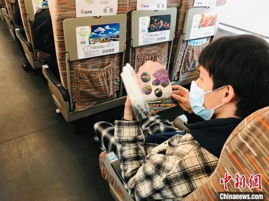 图为旅客观看《鄂尔多斯四季赏花文旅活动》宣传册。 刘奇 摄