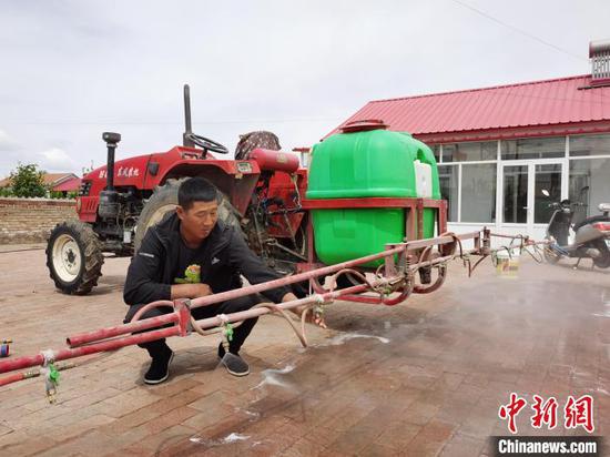 图为赵洪民在调试玉米打药机。 胡建华 摄