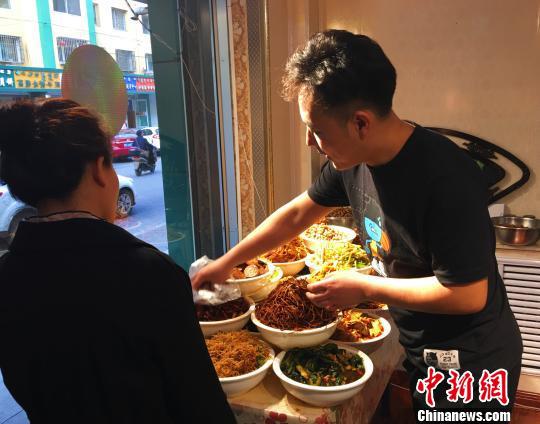 图为张龙为客人挑选咸菜。 张玮 摄