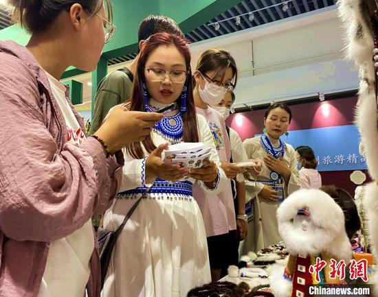 图为游客关注鄂温克族民族手工艺--“太阳花”的展位。 张玮 摄