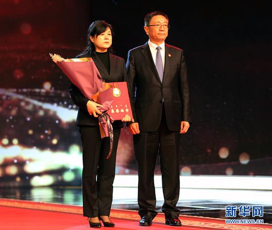 内蒙古自治区党委常委、宣传部部长白玉刚(右)为王晓东家人颁发北疆楷模荣誉证书和奖章。新华网 石毅 摄
