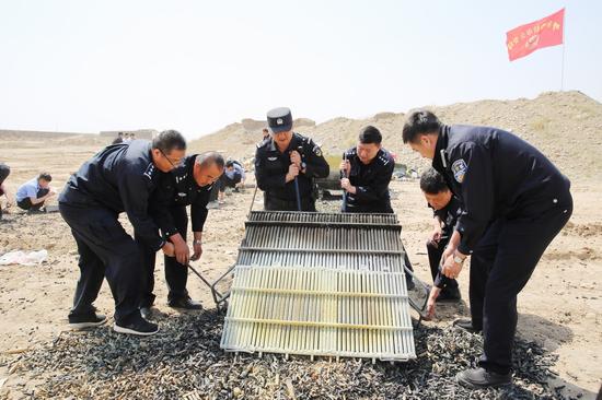 民警现场清理“就地简易笼式烧毁法”销毁的弹药残壳
