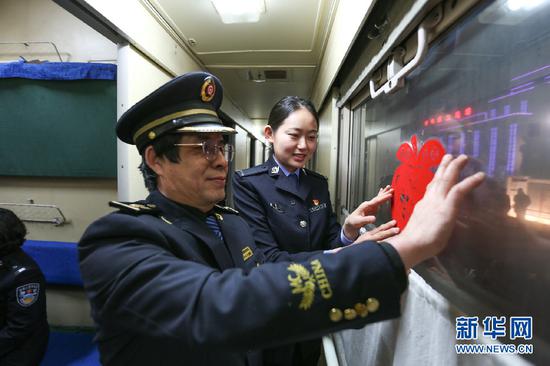 边检民警和列车员一起装饰列车。新华网发(朱宇奇摄)