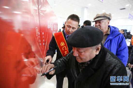 归国返乡旅客在国门留言板上签名。新华网发(朱宇奇摄)