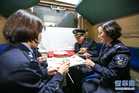 边检民警和列车长孙国祥(右二)一起在列车上吃饺子。新华网发(郭鹏杰摄)
