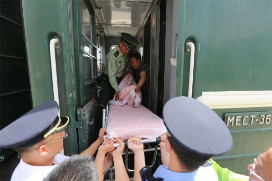 官兵用被子将患病旅客从列车上抬下。