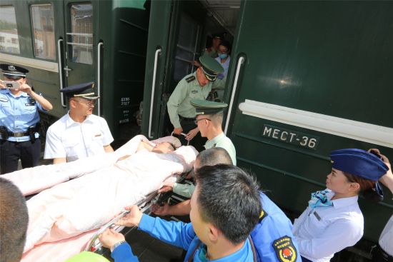 官兵用被子将患病旅客从列车上抬下。