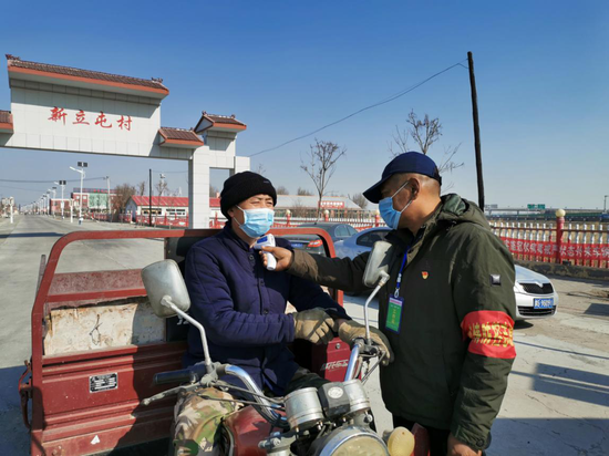 红星街道新立屯村党支部书记代海朝为村民测量体温