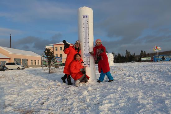 游客在根河冷极村雪雕前拍照留念