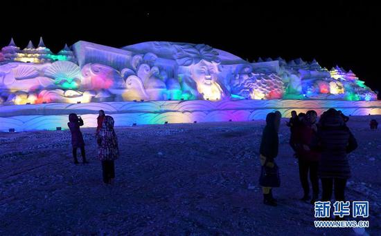 游客在包头市固阳县冰雪文化旅游节上欣赏大型雪雕