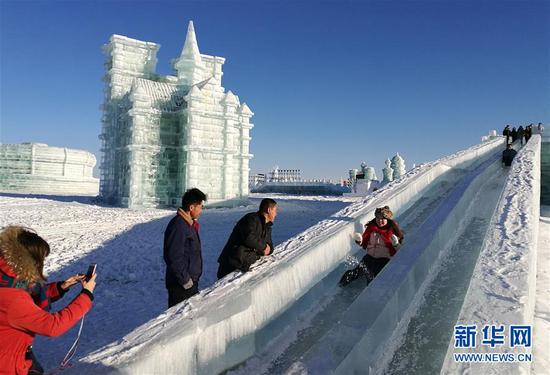 游客在包头市固阳县冰雪文化旅游节现场玩冰滑梯