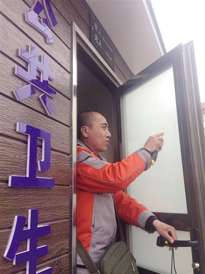 工作人员在清理公厕门上的乱涂乱画