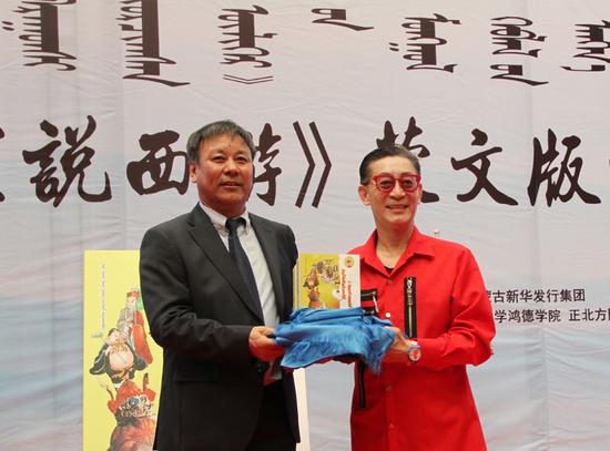 内蒙古日报社副总编辑乌日吐那斯图向章金莱先生(右一)转交100套《听孙悟空说西游》蒙文版图书。