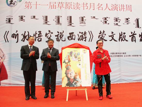 内蒙古日报社副总编辑乌日吐那斯图(左二),伊利集团企业事务部公共事务总监韩飞(左一)与章金莱先生(右一)共同为《听孙悟空说西游》蒙文版图书揭幕。