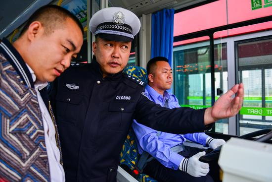 随车测试的警官正与公交公司的工作人员针对路况、速度等方面进行交流