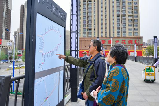 看到快速公交上了路,过往的市民停下脚步对天桥上的公交路线图研究了起来