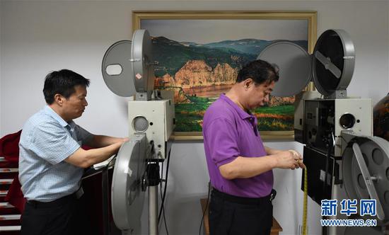 内蒙古电影博物馆的两位创办人宋呼生(左)、杨保华(右)为放映老电影做准备(6月10日摄)。