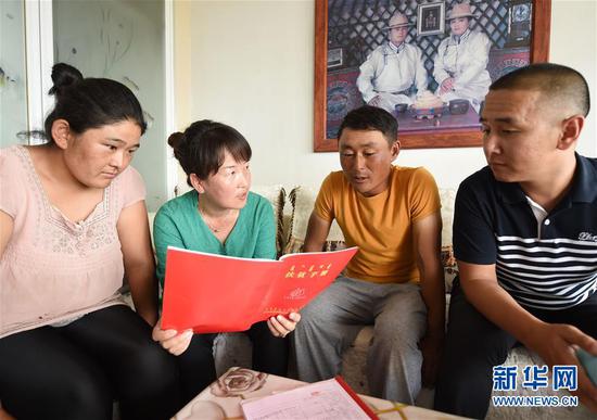 苏尼特右旗农牧业局副局长、嘎查第一书记乌日娜(左二)和吉日木图的脱贫包扶责任人、旗农技推广站长武玉柱(右一)在了解吉日木图目前的生产情况(7月12日摄)。