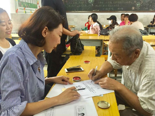 发放现场工作人员和陈志宏老人确认信息,并签字