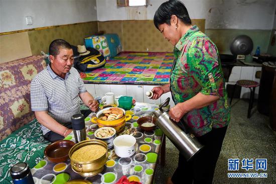 阿迪亚(左)和妻子娜仁其其格在家中喝奶茶(6月21日摄)。