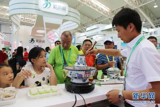 市民在包头国际牛羊肉产业大会展区内品尝涮羊肉。