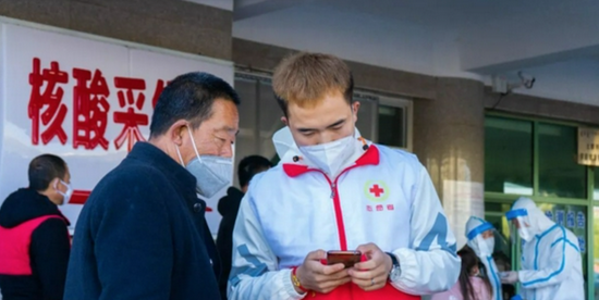 志愿者幫助不會使用智能手機掃碼的群眾進行掃碼登記