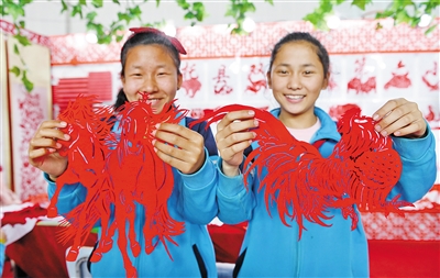 呼和浩特市托克托县双河镇第六小学的同学展示她们的剪纸作品。