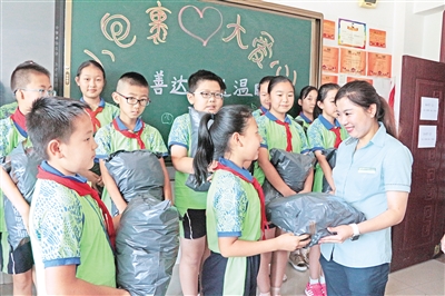 7月11日,呼和浩特市赛罕区金桥小学的孩子们将筹集到的爱心包裹送到邮递员阿姨手中,希望能为需要帮助的人送去一份温暖与关爱。摄影/本报记者 辛永红