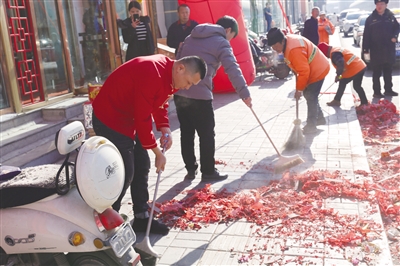 饭店工作人员配合环卫工人清理爆竹碎屑