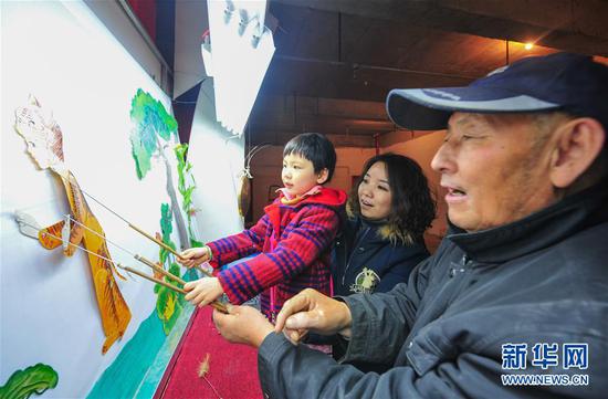市民带着孩子在呼和浩特市大召文化庙会上体验皮影戏