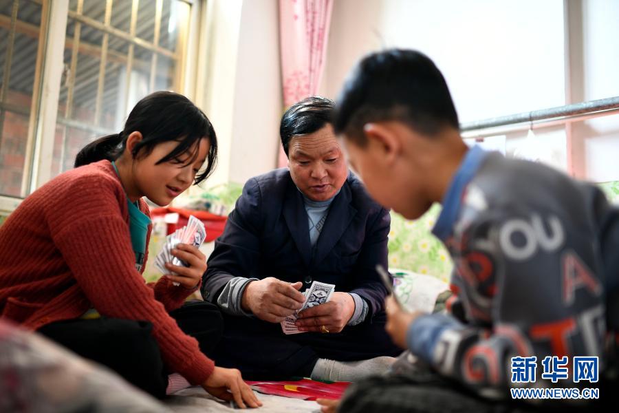2月11日,张俊明在滨河家园移民村的家中与家人打扑克。